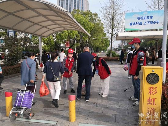 志愿服務(wù)隊(duì)在人民醫(yī)院路口開展文明交通體驗(yàn)活動(dòng)，并幫助老人提重物.jpg.jpg